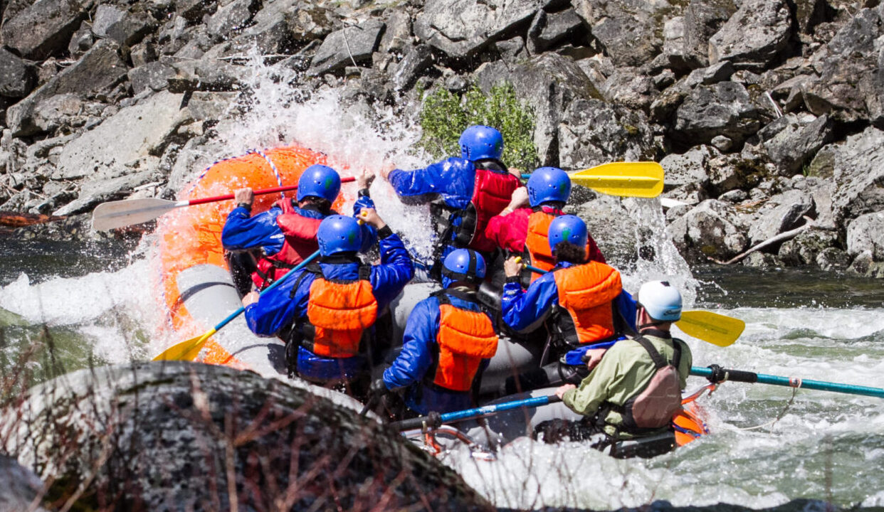 150509113631-2 A group of people wearing helmets and life jackets paddle a raft through whitewater rapids surrounded by rocks, enjoying one of the thrilling Lochsa River attractions.