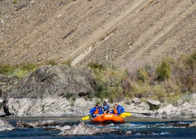 A group of rafters navigates a scenic section of the Alberton Gorge, paddling through calm waters before hitting the next rapid.