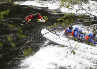 Lochsa River whitewater rafting trip paddlers in helmets brace for the rapid.