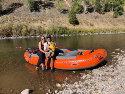 Family-Friendly Floating on the Blackfoot River A family with a young child sits on an orange raft along the Blackfoot River, enjoying a peaceful day on the water.
