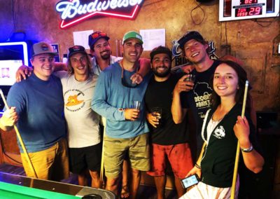 The staff of Zoo Town Surfers is pictured at a bar holding pool sticks and drinks. They are with the (former) owner Jason Shreder.