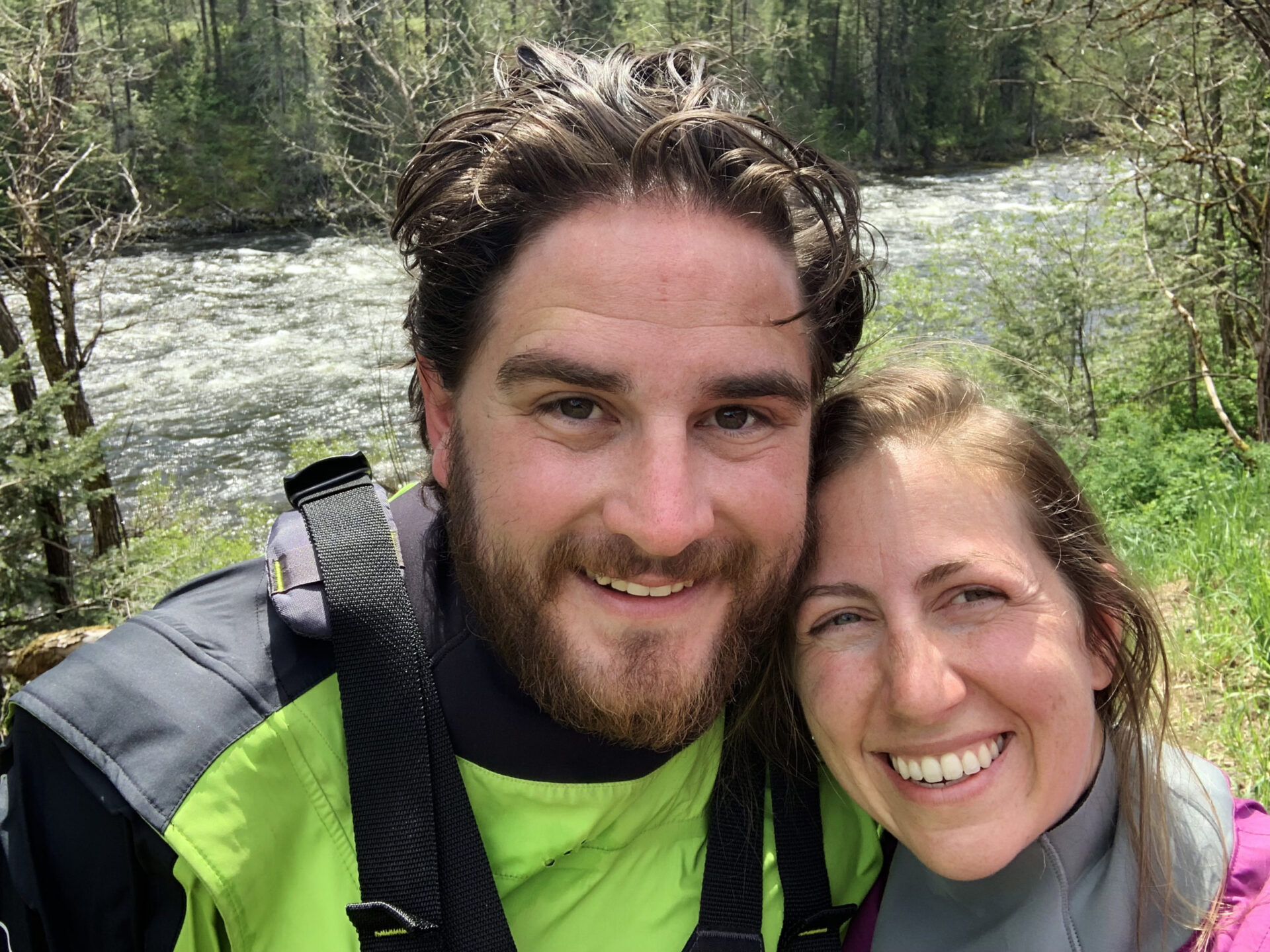 Ian and Megan the owners of Zoo Town Surfers are smiling in their drysuits with the Lochsa River in the background.